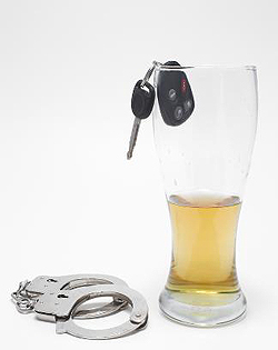 A glass of beer with car keys and handcuffs